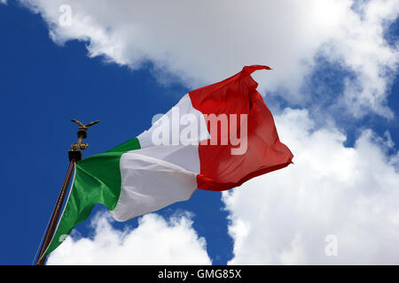 Bandiera Italiana contro un cielo azzurro con soffici nuvole Foto Stock