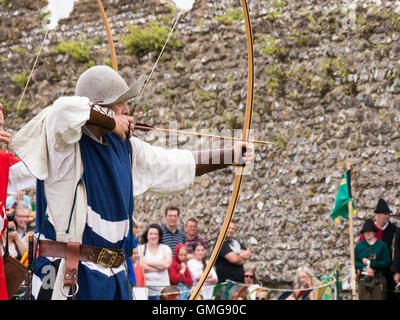 Un reenactor medievale visualizza longbow tecniche di tiro con l'arco all'interno del terreno di Portchester Castle, Inghilterra Foto Stock