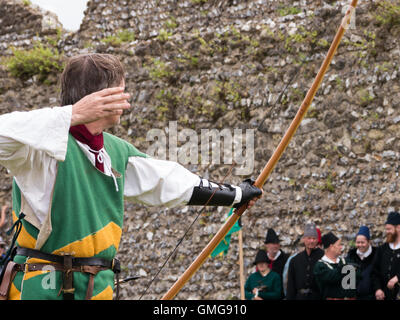 Un reenactor medievale visualizza longbow tecniche di tiro con l'arco all'interno del terreno di Portchester Castle, Inghilterra Foto Stock