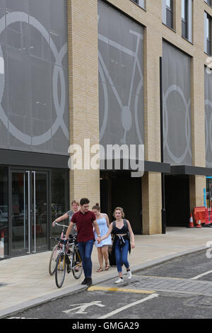 Esterno di un nuovo multi-storey bike park a Cambridge nel Regno Unito. Mostra giovani che lasciano con la bici. Caratteristiche del logo del ciclo sulla facciata Foto Stock