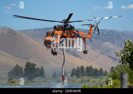 L'elicottero da combattimento Erickson Helitanker utilizza il suo snorkeling per riempire il serbatoio d'acqua mentre combatte il fuoco selvatico Clark, California, USA Foto Stock