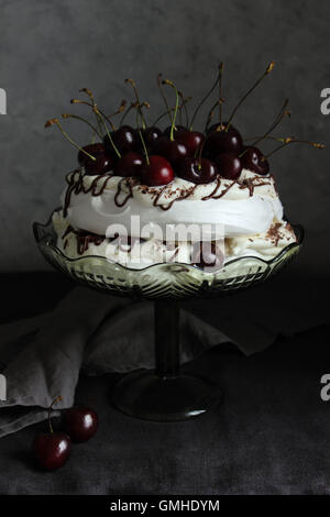 In casa la ciliegia Pavlova meringa torta con dark in salsa di cioccolato e crema di mascarpone Foto Stock