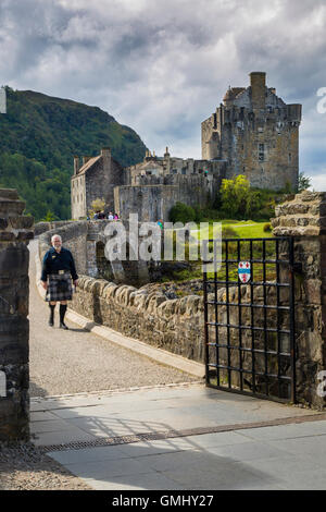 Uomo in un kilt passeggiate attraverso il ponte dal Castello Eilean Donan, Highlands, Scotland, Regno Unito Foto Stock