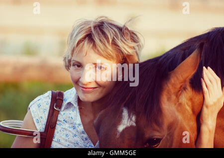 Donna in hat kissing marrone a cavallo. Vintage immagine filtrata. Foto Stock