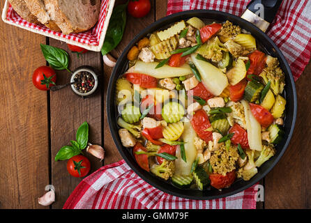 Menu dietetici. Verdure al vapore con filetto di pollo nella padella sullo sfondo di legno. Vista superiore Foto Stock