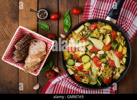 Menu dietetici. Verdure al vapore con filetto di pollo nella padella sullo sfondo di legno. Vista superiore Foto Stock