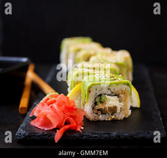 Tradizionale cibo giapponese - sushi, rotoli e salsa su uno sfondo nero. Foto Stock