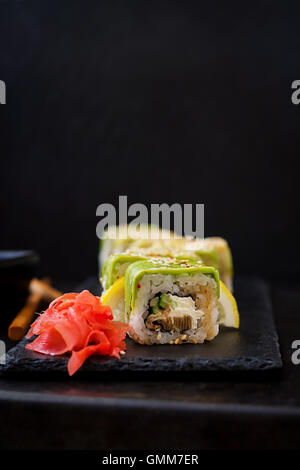Tradizionale cibo giapponese - sushi, rotoli e salsa su uno sfondo nero. Foto Stock