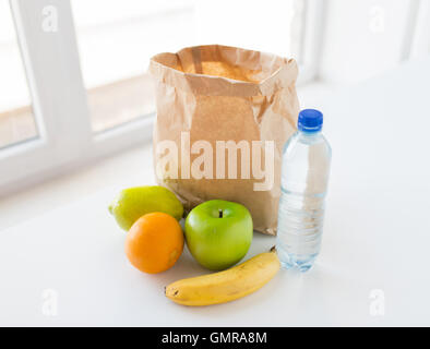 Cesto di freschi frutti maturi e acqua in cucina Foto Stock