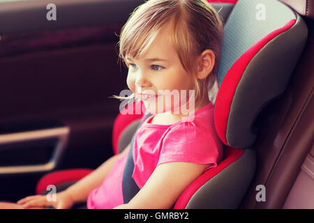 Piccolo felice ragazza seduta nella baby car seat Foto Stock