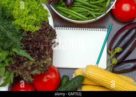 Notebook per le ricette sul tavolo fra le verdure Foto Stock