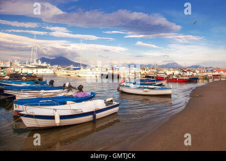 La spiaggia di fronte al porto di Napoli, con le barche a vela e barche a motore ormeggiata sulla riva del mare. Sullo sfondo il vulcano Foto Stock