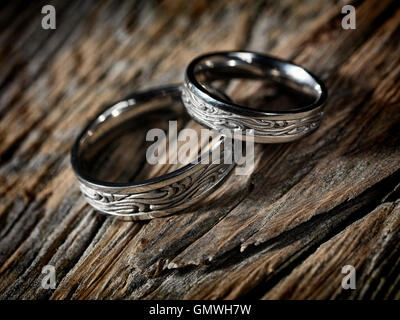 Due oro bianco anelli di nozze con Celtic design in legno rustico sfondo artistico, still life Foto Stock