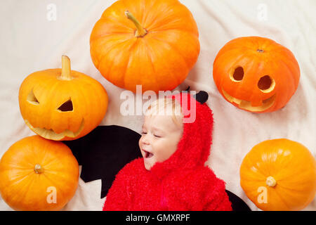 Bambino in costume diavolo con zucche Foto Stock