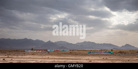 Montagne e deserto con il Farsi segni sulle pareti abbandonate ed edifici vicino a Na'in Iran. Foto Stock