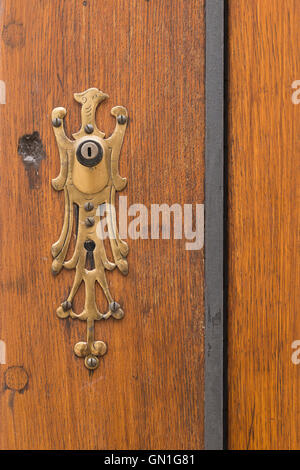 Primo piano di un marrone porta di legno con un intricato foro chiave decorazione in forma di un uccello. Foto Stock