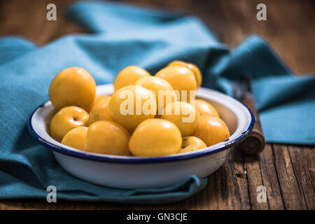 Fresche e mature prugne giallo nel recipiente Foto Stock