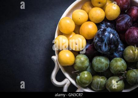 Vivace e susine mature nel recipiente dal mercato locale Foto Stock