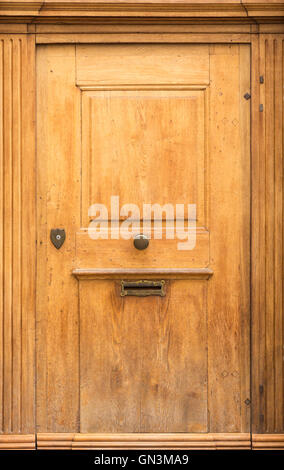 Il vecchio in legno marrone chiaro con porta di metallo circolare la manopola e la casella di posta elettronica fessura. Foto Stock