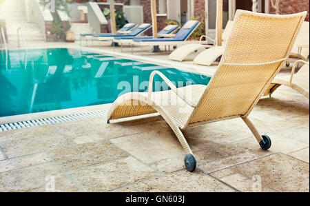 Lettini vicino a una piscina per rilassarsi in estate Foto Stock