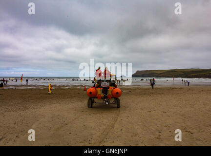 Due donne bagnini RNLI mantenere guardare come le persone imparano a navigare su una fredda mattina d'estate a Polzeath Beach, North Cornwall, Regno Unito Foto Stock
