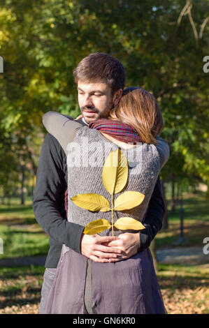 Amare giovane costeggiata nel parco mentre si tiene il giallo Foglie di autunno Foto Stock