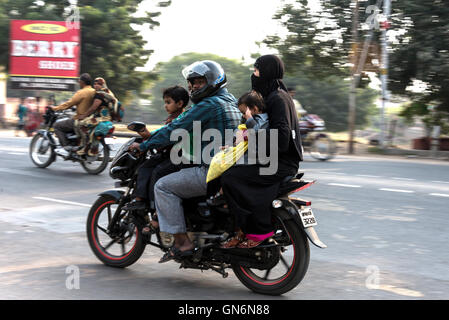 Una famiglia di quattro persone tra cui un bambino cavalca un motociclo costruito per due a Agra in Uttar Pradesh, India Foto Stock