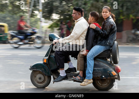 Tre su uno scooter progettato per due sulla trafficata strada principale di Agra in Uttar Pradesh, India. Foto Stock