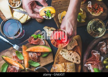 Il vino italiano snack varietà dell'uomo, tenendo le mani un bicchiere di rose Foto Stock