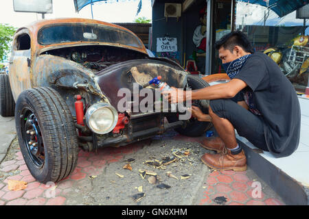 BALI, Indonesia - 20 Marzo: giovane uomo Balinese purifica il corpo di una vecchia Volkswagen maggiolino durante la realizzazione vintage auto personalizzata. Foto Stock