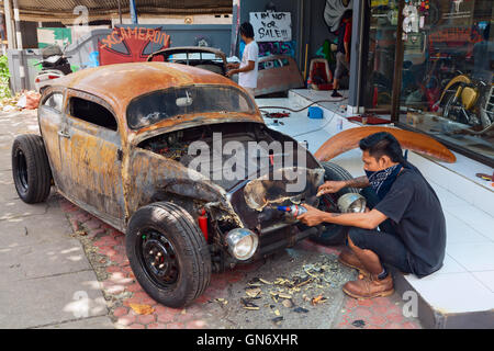 BALI, Indonesia - 20 Marzo: giovane uomo Balinese purifica il corpo di una vecchia Volkswagen maggiolino durante la realizzazione vintage hotrod personalizzato auto. Foto Stock