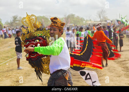 Sanur, isola di Bali, Indonesia - 15 Luglio 2012: uomo Balinese il lancio di kite con testa di drago mitico e lunga coda. Foto Stock