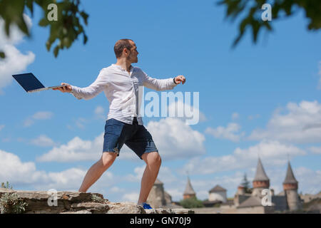 L'uomo getta notebook contro il cielo blu Foto Stock