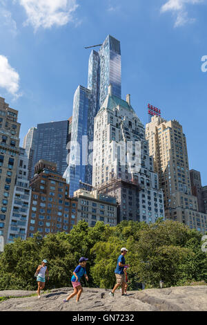 Il grattacielo residenziale uno57 torreggia su una famiglia arrampicata sulle rocce di Central Park e di altri edifici vicini sulla West 57th Street a New York City. Foto Stock