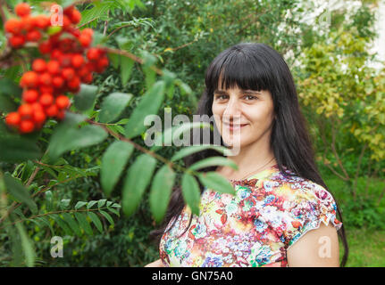 Ritratto di una giovane e bella bruna vicino a rowan tree Foto Stock