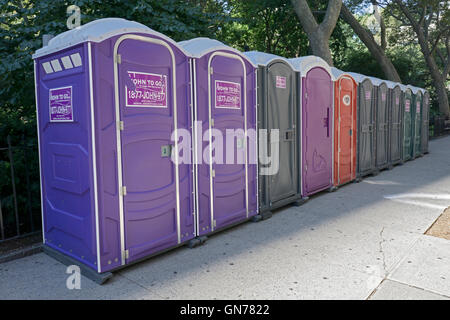 Una colorata fila di servizi igienici portatili fuori dal Madison Square Park a Manhattan, New York City Foto Stock