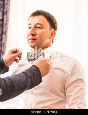 Groomsman aiutare lo sposo a mettere su il filtro bow tie Foto Stock