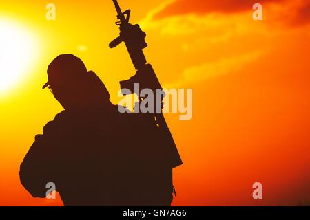 Moderna ed attrezzata soldato con fucile Silhouette al tramonto. Concetto militare Foto Stock