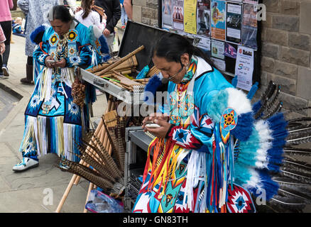 Aztec Pan Pipers controllo dei messaggi su telefoni intelligenti durante un intervallo durante il loro street performance Foto Stock