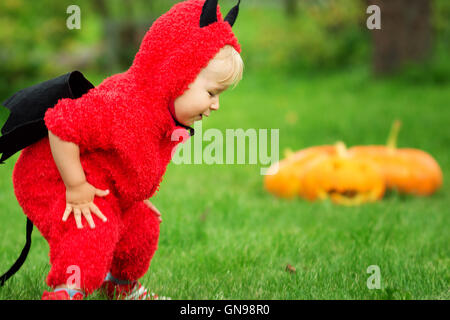 Bambino in costume diavolo con zucche Foto Stock