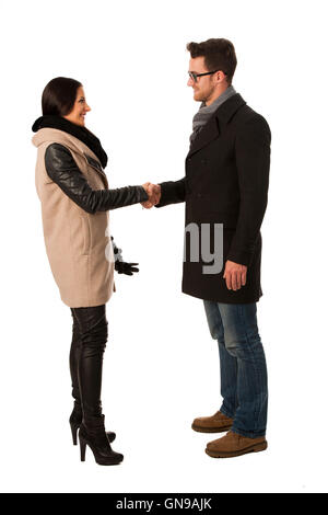 Due persone vestite di cappotto invernale si stringono la mano in segno di accordo commerciale. Foto Stock