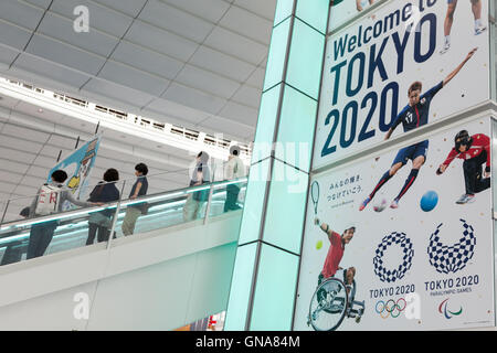 I viaggiatori a piedi passato a Tokyo Giochi Olimpici e Paraolimpici pubblicità su display a Tokyo International Airport il 30 agosto 2016, Tokyo, Giappone. Tra il 24 agosto e 10 ottobre l'aeroporto è la visualizzazione di molte Benvenuto a Tokyo 2020 indicazioni per promuovere il 2020 Giochi olimpici estivi. © Rodrigo Reyes Marin/AFLO/Alamy Live News Foto Stock