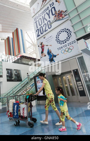 I viaggiatori a piedi passato a Tokyo Olimpiadi pubblicità su display a Tokyo International Airport il 30 agosto 2016, Tokyo, Giappone. Tra il 24 agosto e 10 ottobre l'aeroporto è la visualizzazione di molte Benvenuto a Tokyo 2020 indicazioni per promuovere il 2020 Giochi olimpici estivi. © Rodrigo Reyes Marin/AFLO/Alamy Live News Foto Stock