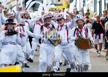 Tre morris fisarmonica giocatori che portano Hartley Morris lato come ballano sventolando hankies bianco durante una parata in città street. Venendo verso il visualizzatore. Foto Stock