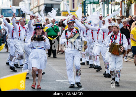 Tre morris fisarmonica giocatori che portano Hartley Morris lato come ballano sventolando hankies bianco durante una parata in città street. Venendo verso il visualizzatore. Foto Stock