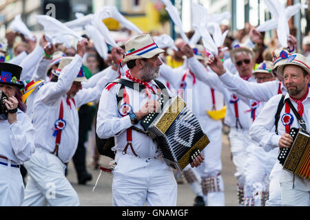 Tre morris fisarmonica giocatori che portano Hartley Morris lato come ballano sventolando hankies bianco durante una parata in città street. Venendo verso il visualizzatore. Foto Stock