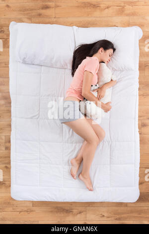Carino giovane donna che dorme sul letto Foto Stock