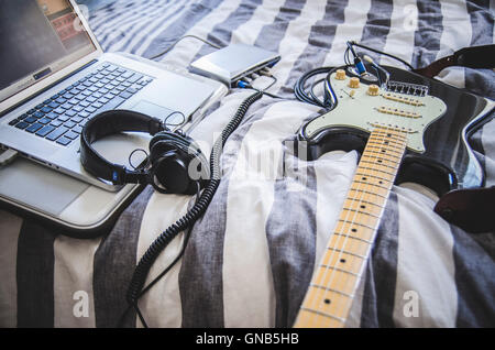 Chitarra elettrica e cuffie collegato in casa di apparecchiature di registrazione e il computer portatile Foto Stock