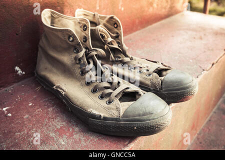 Coppia di vecchi sneakers in piedi sul cemento rosso scale, closeup foto con messa a fuoco selettiva Foto Stock