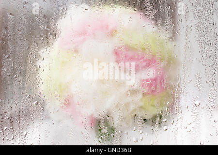 Sfocata bouquet di rose dietro una piccola goccia d'acqua specchio. Foto Stock